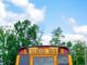 school bus near green trees under cloudy sky during daytime