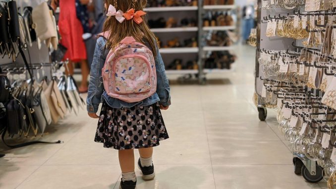 girl in pink and blue floral dress standing on white floor tiles
